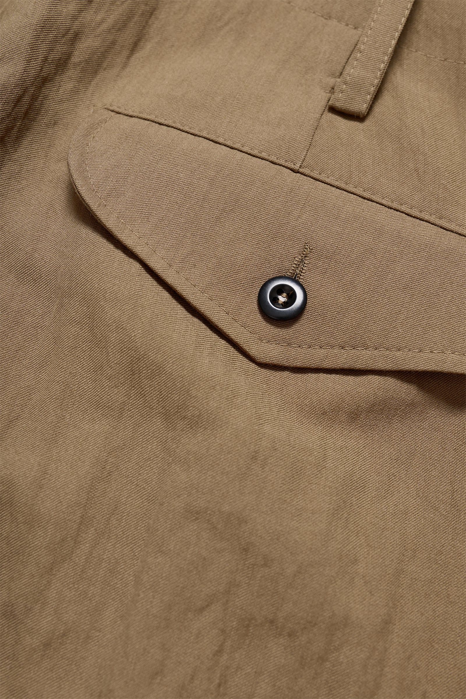 Close-up of a khaki shirt pocket with a dark button